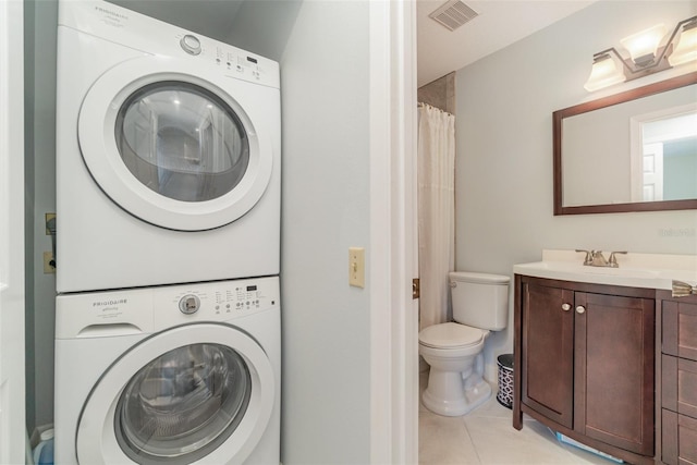 clothes washing area featuring stacked washer and dryer, sink, and light tile patterned floors