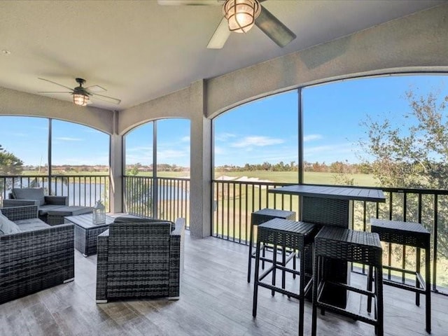 sunroom with a water view and ceiling fan