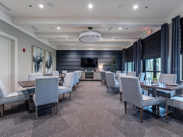 carpeted dining space with beamed ceiling and wood walls