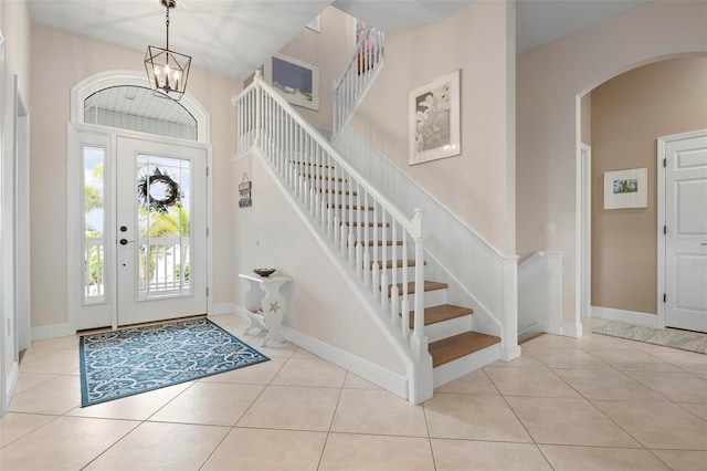 entrance foyer with light tile patterned floors, a notable chandelier, and a high ceiling