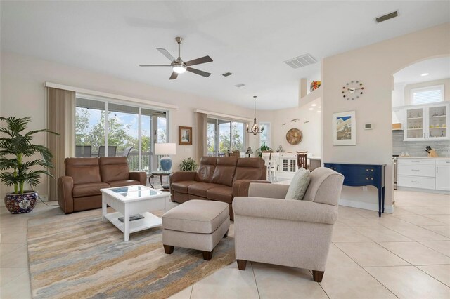 living room with light tile patterned flooring and ceiling fan with notable chandelier