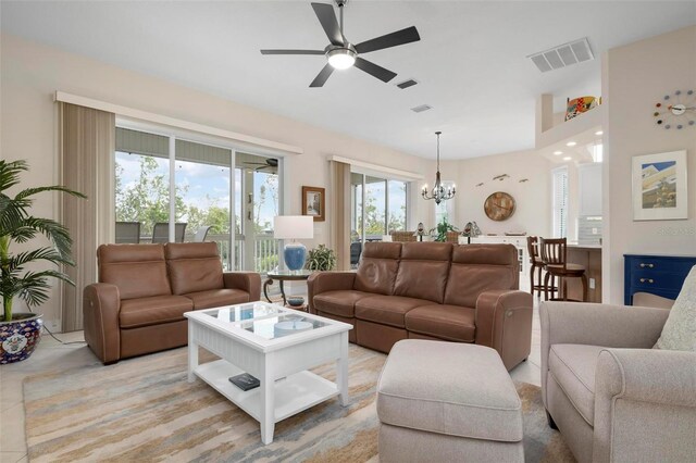 living room featuring light tile patterned floors and ceiling fan with notable chandelier