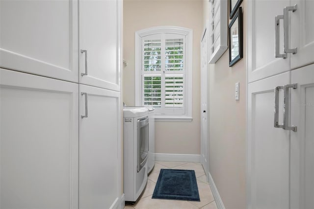 washroom featuring cabinets, light tile patterned floors, and washing machine and clothes dryer