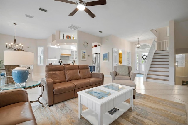 living room with light tile patterned floors, ceiling fan with notable chandelier, and vaulted ceiling