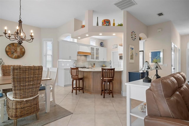 kitchen with pendant lighting, backsplash, light tile patterned floors, and white cabinets