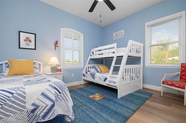 bedroom with multiple windows, wood-type flooring, and ceiling fan