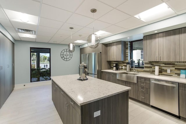 kitchen with a center island, decorative light fixtures, stainless steel appliances, tasteful backsplash, and sink