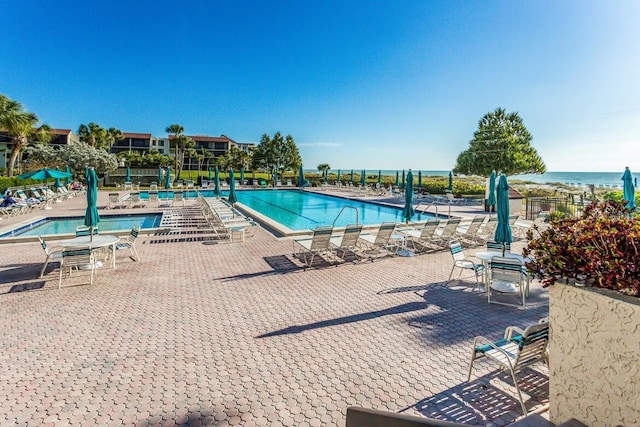 view of swimming pool featuring a patio area and a water view