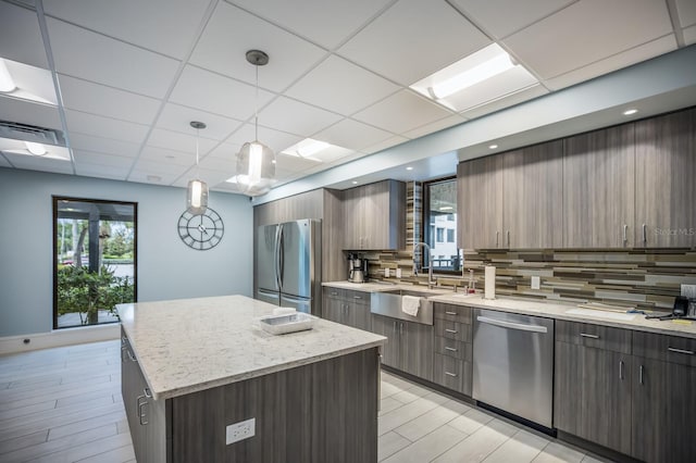 kitchen with a kitchen island, decorative backsplash, sink, hanging light fixtures, and stainless steel appliances