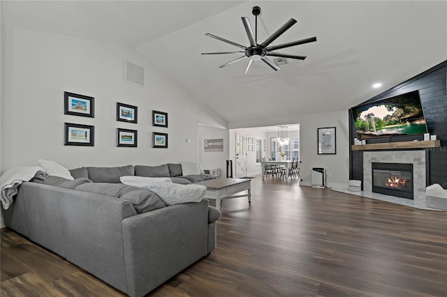 living room featuring a tiled fireplace, ceiling fan, vaulted ceiling, and dark wood-type flooring