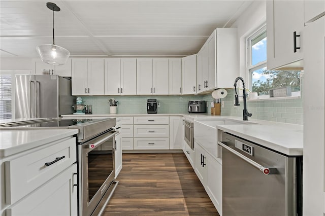 kitchen with appliances with stainless steel finishes, dark hardwood / wood-style floors, white cabinets, decorative light fixtures, and tasteful backsplash