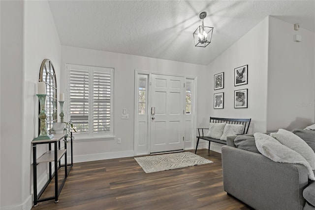 entrance foyer with a textured ceiling, a chandelier, vaulted ceiling, and dark hardwood / wood-style floors