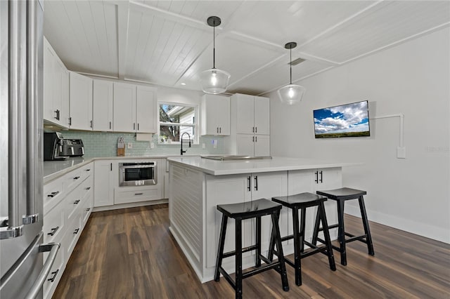 kitchen featuring a kitchen island, white cabinetry, backsplash, and hanging light fixtures