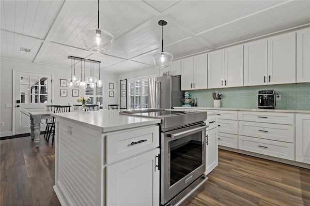 kitchen featuring appliances with stainless steel finishes, pendant lighting, white cabinetry, and decorative backsplash