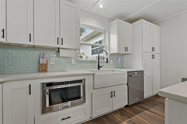 kitchen featuring sink, white cabinetry, backsplash, dark hardwood / wood-style floors, and appliances with stainless steel finishes