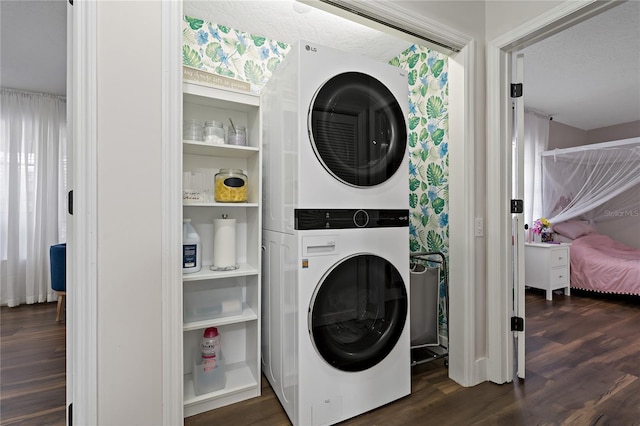 clothes washing area with dark hardwood / wood-style flooring, stacked washing maching and dryer, and a textured ceiling