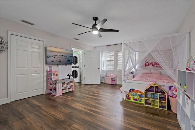 game room featuring a textured ceiling, ceiling fan, stacked washer and clothes dryer, and dark hardwood / wood-style floors