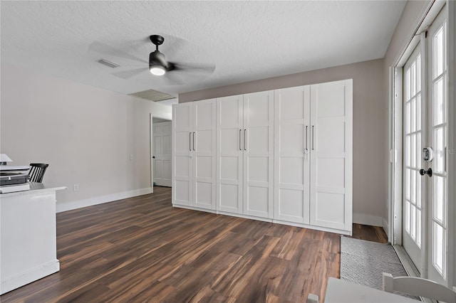 unfurnished office with ceiling fan, dark wood-type flooring, a textured ceiling, and plenty of natural light