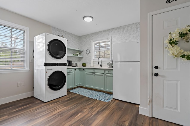 laundry area with sink, cabinets, stacked washer / dryer, and dark hardwood / wood-style floors