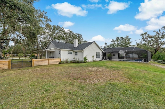 back of property with glass enclosure and a lawn