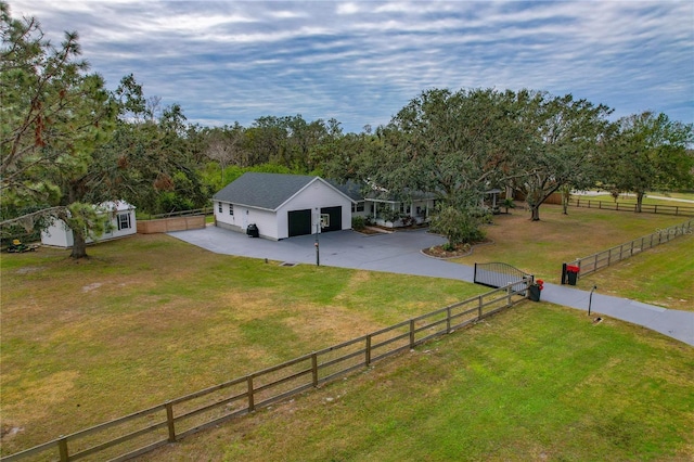 view of front of property featuring a rural view, a front lawn, a garage, and an outdoor structure