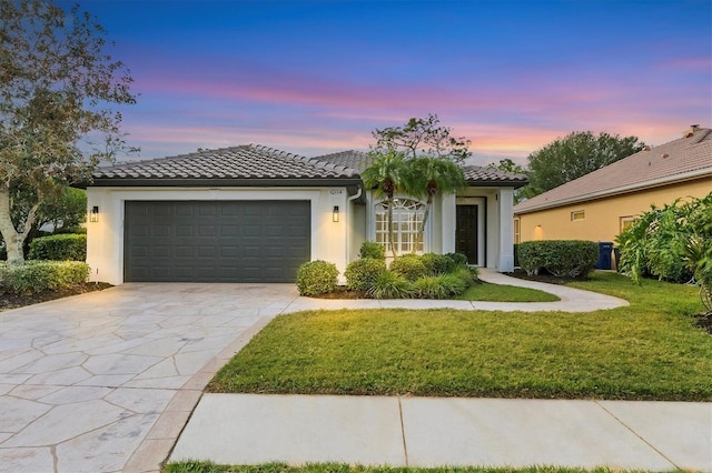 mediterranean / spanish-style house featuring a garage and a lawn