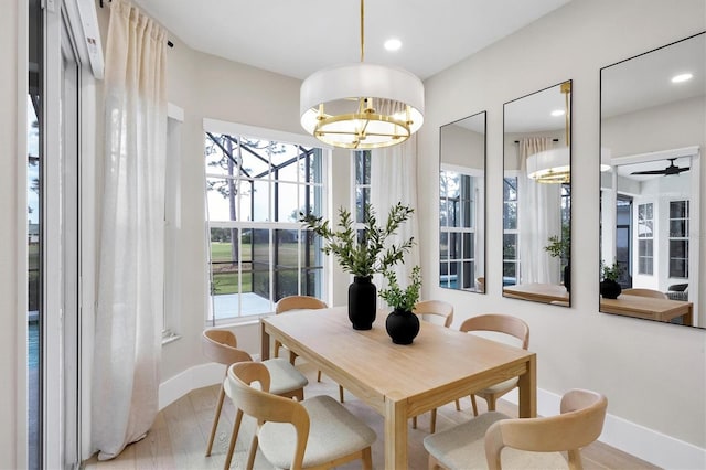 dining area with light hardwood / wood-style floors, plenty of natural light, and ceiling fan with notable chandelier