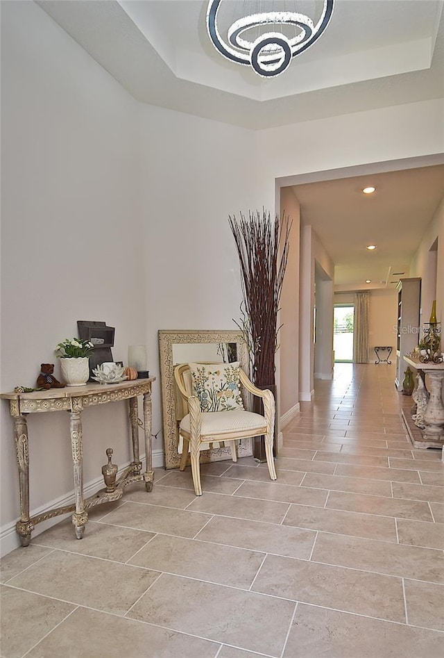 corridor with a tray ceiling and a chandelier