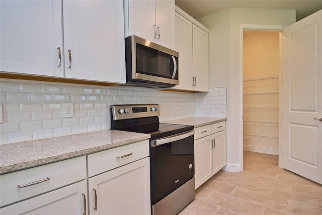 kitchen with tasteful backsplash, stainless steel appliances, white cabinetry, and light stone counters