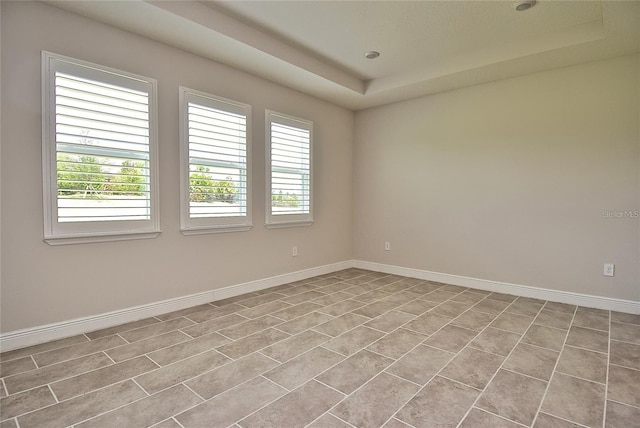 tiled spare room featuring a tray ceiling