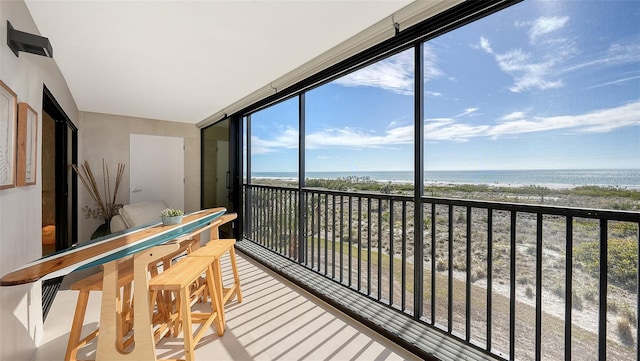 sunroom featuring a view of the beach and a water view