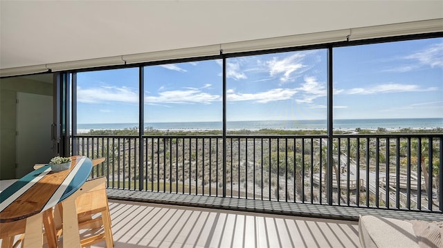 unfurnished sunroom with a view of the beach, a healthy amount of sunlight, and a water view