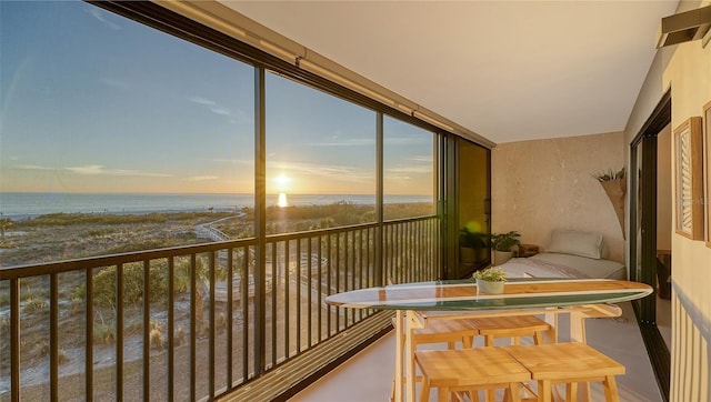 balcony at dusk featuring a water view