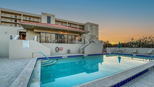 pool at dusk featuring a patio area