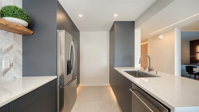 kitchen with sink, light tile patterned floors, appliances with stainless steel finishes, backsplash, and light stone counters