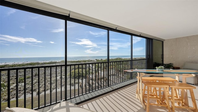 sunroom / solarium featuring a water view and a beach view