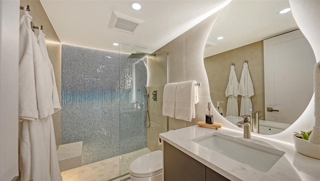 bathroom featuring vanity, tiled shower, and toilet