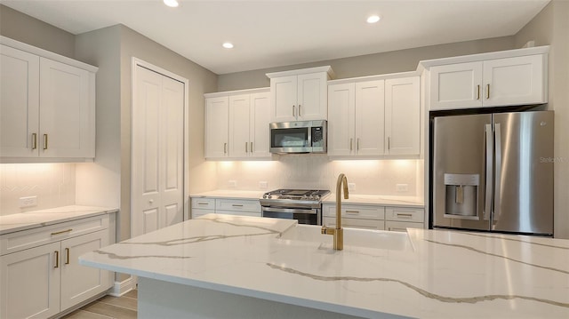 kitchen with sink, stainless steel appliances, light stone countertops, and white cabinetry