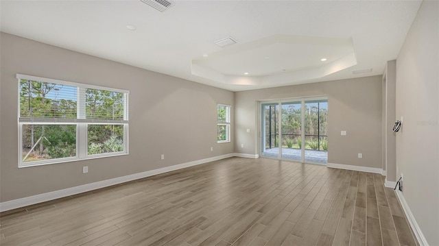 unfurnished room featuring a tray ceiling and light hardwood / wood-style floors