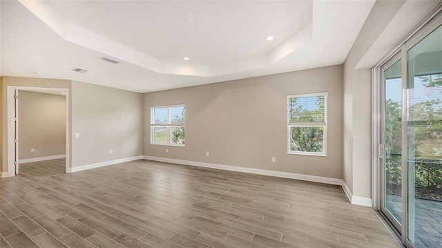 spare room with light hardwood / wood-style floors and a tray ceiling