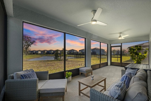 sunroom / solarium featuring ceiling fan and a water view