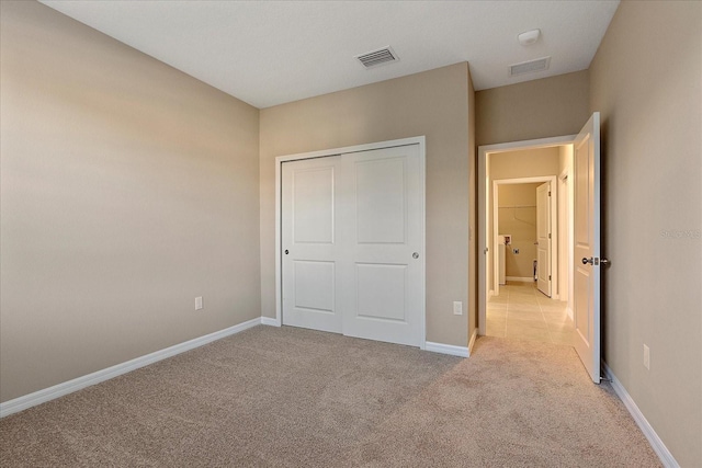 unfurnished bedroom with light colored carpet and a closet