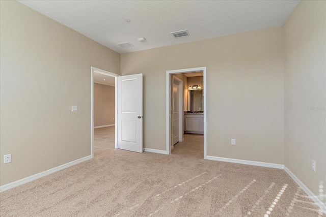 unfurnished bedroom with light carpet and a textured ceiling