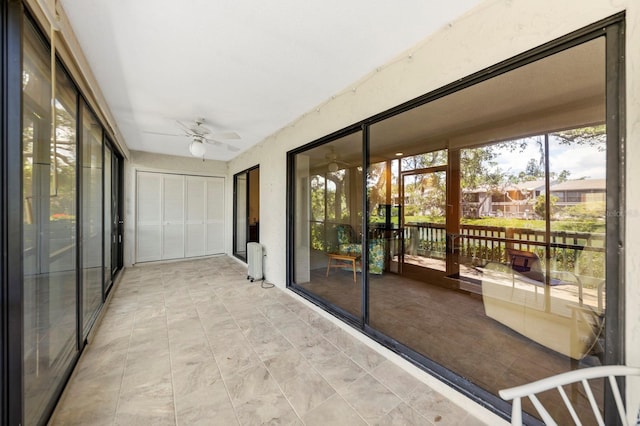 unfurnished sunroom with ceiling fan, radiator, and plenty of natural light