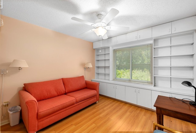 living room featuring a textured ceiling, ceiling fan, and light hardwood / wood-style floors