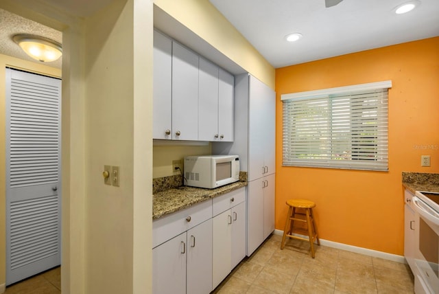 kitchen with white appliances, white cabinets, and stone countertops