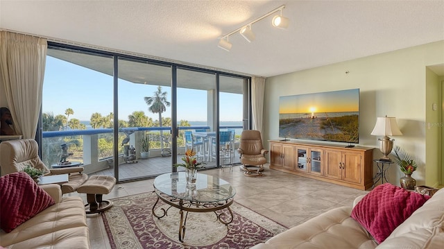 living room featuring floor to ceiling windows, rail lighting, light tile patterned floors, and a textured ceiling