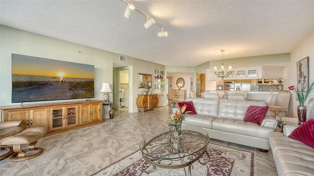 living room featuring an inviting chandelier and a textured ceiling