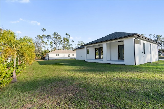 back of property featuring ceiling fan and a lawn