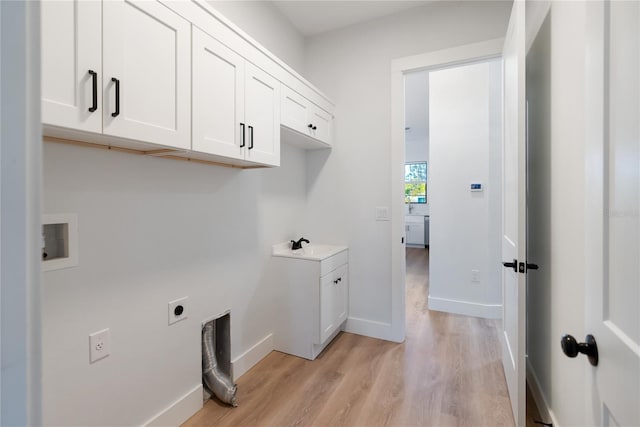 laundry area featuring cabinets, washer hookup, sink, hookup for an electric dryer, and light hardwood / wood-style flooring